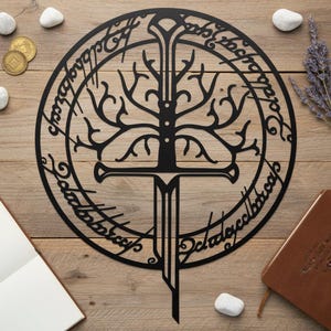 May include: Black metal wall art featuring a tree design with a sword, encircled by text. The artwork is set against a wooden background, with coins, stones, a notebook, and lavender sprigs. The design is inspired by fantasy themes.