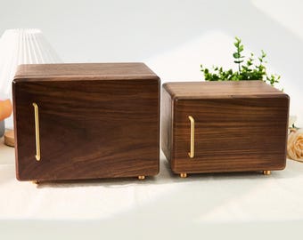 May include: Two wooden boxes with a rich, dark brown finish. Each box has a gold-colored handle and small feet. The boxes are rectangular and appear to be made of solid wood, showcasing the natural grain.