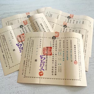 May include: A collection of vintage Japanese fire insurance documents printed on off-white paper. Each document features black Japanese text, decorative borders, and multiple red ink stamps. Some documents include handwritten purple ink signatures.