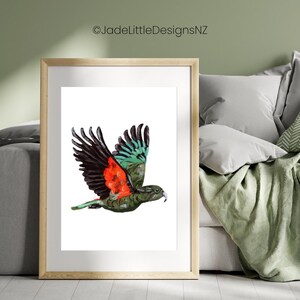 May include: A framed watercolor print of a bird in flight. The bird has black and green wings, a red chest, and a green body. The artwork is set against a white background and framed in a light wood frame.