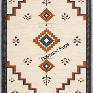 May include: Cream-colored rectangular rug with a geometric pattern. The design features diamond shapes in shades of brown and navy blue, with a border of dark gray. The rug has a fringe on the bottom edge and the text "Diamond Rugs".