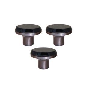 Puede incluir: Tres tiradores de armario con una parte superior negra y redondeada y una base de metal cepillado. Los tiradores están dispuestos en un patrón triangular sobre un fondo blanco. Los tiradores son probablemente para muebles o armarios.