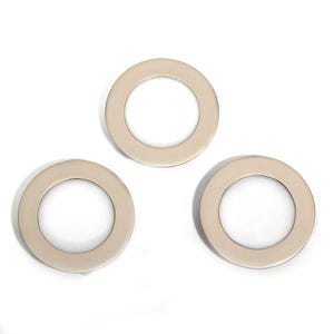 May include: Three metallic, circular rings with a flat, beveled edge. The rings are a light, neutral color, possibly silver or gold, and are evenly spaced against a white background. The design is simple and modern.