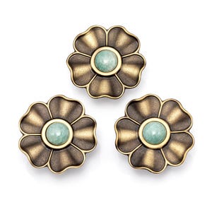 Könnte beinhalten: Drei bronzefarbene, blütenförmige Schrankknöpfe mit einem hellgrünen, kreisförmigen Mittelteil. Die Knöpfe haben ein detailliertes, blütenblattartiges Design und eine Vintage-Ästhetik. Ideal, um Möbeln eine dekorative Note zu verleihen.