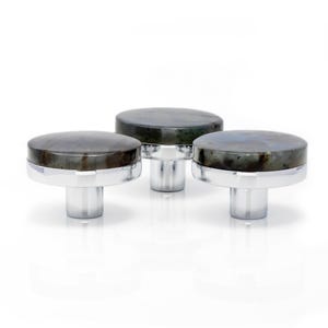 Puede incluir: Tres pomos decorativos para armarios con una parte superior redonda de piedra gris oscuro y una base plateada. Los pomos están agrupados, destacando su diseño y su uso potencial en la decoración del hogar.