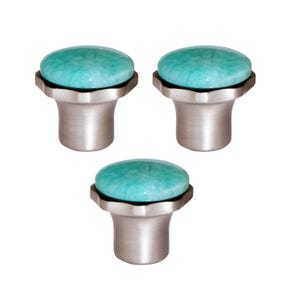 May include: Three cabinet knobs featuring a teal, oval stone top and a brushed silver base. The knobs have a decorative, scalloped edge where the stone meets the base. These knobs are a decorative hardware option for cabinets and drawers.