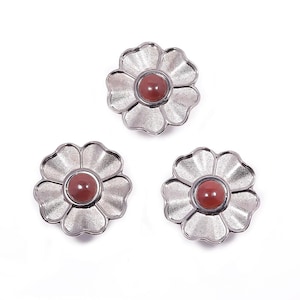 Può includere: Tre abbellimenti argentati a forma di fiore con un centro marrone rossiccio. I petali hanno un aspetto strutturato e la pietra centrale è liscia e rotonda. Questi pezzi decorativi potrebbero essere utilizzati per l'artigianato o la gioielleria.