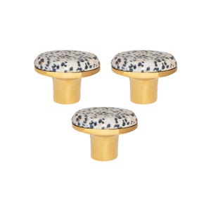 May include: Three cabinet knobs with a speckled, off-white top with black and tan spots, a gold-coloured rim, and a gold-coloured base. These decorative knobs are designed for furniture and home decor. Each knob is a unique design.