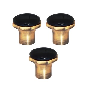 May include: Three cabinet knobs featuring a black, oval top and a bronze-coloured base. These knobs have a classic design, suitable for drawers or cabinet doors. The bronze finish adds a vintage touch to furniture.