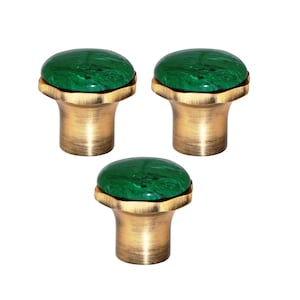 May include: Three cabinet knobs with a green, marbled stone top and a brass-coloured base. The knobs have a rounded top and a cylindrical base, suitable for furniture or decor.