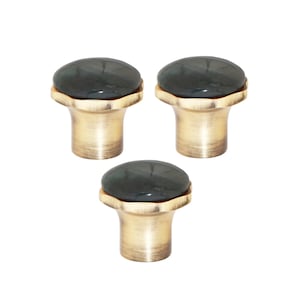 May include: Three cabinet knobs with a dark green, oval stone top and a brass-coloured base. The knobs have a classic design, suitable for drawers or cabinet doors. The knobs are set against a white background.