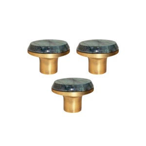 May include: Three cabinet knobs with a brass base and a dark green, marbled stone top. The knobs have a rounded shape and are set against a white background. These decorative knobs are suitable for furniture and home decor.