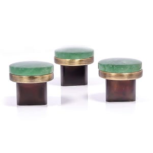 May include: Three decorative stools with a green top, a gold-colored band, and a dark brown base. The stools are arranged in a row against a white background. The design is modern and elegant.