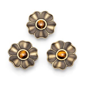 Op de afbeelding: Drie decoratieve bloemvormige kastknoppen. Elke knop heeft een bronzen metalen bloemontwerp met een centrale, ronde tijgeroogsteen. De knoppen zijn gerangschikt op een witte achtergrond.
