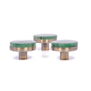 May include: Three cabinet knobs with a circular, green top and a brass base. The knobs are displayed against a white backdrop. These knobs are likely for furniture or home decor. The knobs are approximately 3 cm in diameter.