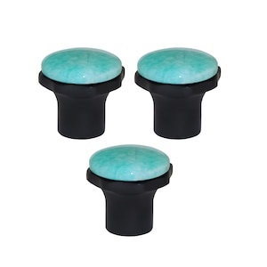 May include: Three cabinet knobs with a light teal stone top and a black base. The knobs are arranged in a triangular pattern. The knobs are suitable for cabinets and drawers. The background is white.