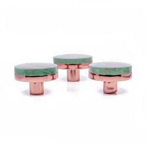 Op de afbeelding: Drie decoratieve kastknoppen. Elke knop heeft een ronde, groene stenen bovenkant met een koperkleurige basis. De knoppen zijn in een rij gerangschikt tegen een witte achtergrond, wat hun ontwerp en kleurcontrast benadrukt.