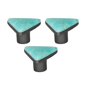 Op de afbeelding: Drie kastknoppen met een driehoekige bovenkant en een donkergrijze basis. De bovenkant heeft een lichtblauw en wit gemarmerd patroon. Deze knoppen zijn een decoratief hardware-element voor meubels.