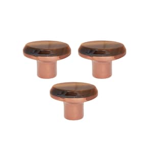 May include: Three cabinet knobs with a copper-coloured base and a brown, oval-shaped top. The knobs are arranged in a triangular pattern against a white background. The tops have a marbled appearance.
