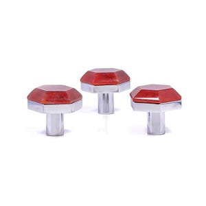 Op de afbeelding: Drie decoratieve kastknoppen met een facetgeslepen, rode, edelsteenachtige bovenkant en een zilverkleurige basis. De knoppen zijn in een rij gerangschikt tegen een witte achtergrond. Deze knoppen zijn geschikt voor meubels of woondecoratie.