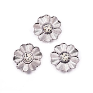 Op de afbeelding: Drie zilverkleurige bloemvormige decoratieve knoppen. Elke knop heeft een centrale, gespikkelde, gebroken witte steen. De bloemblaadjes hebben een textuur. De knoppen zijn op een witte achtergrond geplaatst.