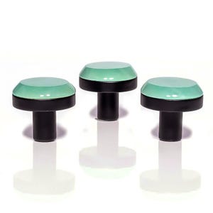 Könnte beinhalten: Drei dekorative Schrankknöpfe. Jeder Knopf hat eine mintgrüne, abgerundete Oberseite mit schwarzem Sockel und Stiel. Die Knöpfe werden vor einem weißen Hintergrund mit ihren darunter sichtbaren Reflexionen dargestellt.
