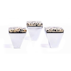 Op de afbeelding: Drie decoratieve kastknoppen met een vierkante, gespikkelde stenen bovenkant in beige en zwart. De basis is van gepolijst, zilverkleurig metaal met een trapeziumvorm. De knoppen staan tegen een witte achtergrond. Elke knop is ongeveer 3 cm breed.