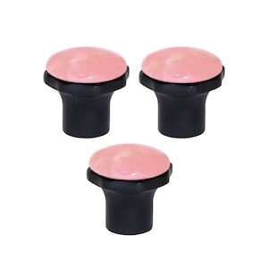 May include: Three black cabinet knobs with a rounded, pink top. The knobs have a simple, modern design, suitable for drawers or cabinets. The pink colour adds a touch of elegance.