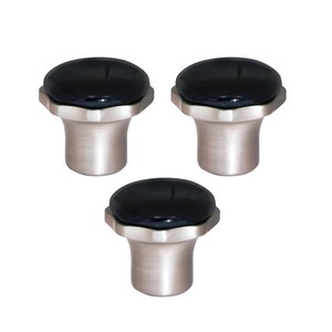 May include: Three cabinet knobs with a brushed metal base and a black, oval-shaped top. The knobs are evenly spaced against a white background, showcasing their design and finish.