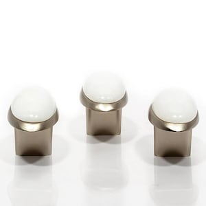 May include: Three cabinet knobs with a white, rounded top and a brushed nickel base. The knobs have a modern design and are set against a white background. The knobs are likely used for drawers or cabinets.