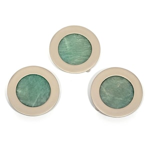 May include: Three round, silver-toned metal buttons with a central, circular inlay of green stone. The buttons are arranged in a triangular pattern against a white background. The stone has a mottled appearance.