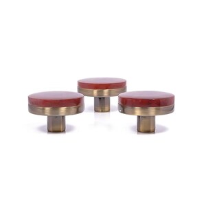 Könnte beinhalten: Drei dekorative Schrankknöpfe. Jeder Knopf hat eine runde, rotbraune Oberseite mit einem messingfarbenen Band und einem messingfarbenen Stiel. Die Knöpfe sind vor einem weißen Hintergrund angeordnet. Durchmesser ca. 3 cm.