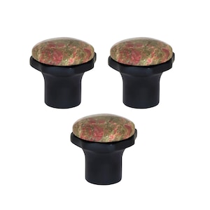 May include: Three cabinet knobs with a black base and a round top made of a speckled red and green stone. The knobs are arranged in a triangular pattern against a white background.