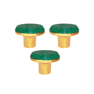 Könnte beinhalten: Drei dekorative Flaschenverschlüsse. Jeder Verschluss hat eine grüne, facettierte Oberseite mit einem goldfarbenen Band und einem goldfarbenen Stiel. Die Verschlüsse sind in einem Dreiecksmuster vor weißem Hintergrund angeordnet.