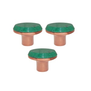 May include: Three cabinet knobs with a green, stone-like top and a copper base. The knobs are arranged in a triangular pattern. The green tops have a mottled appearance. The knobs are suitable for drawers or cabinets.