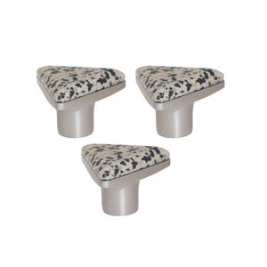 Op de afbeelding: Drie kastknoppen met een driehoekige bovenkant met een gespikkeld patroon in zwart, grijs en crème. De knoppen hebben een basis van geborsteld metaal, voor meubels of kasten.