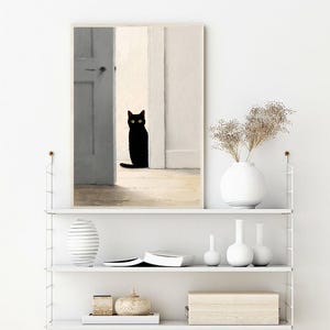 Peut inclure: Une impression d'art encadr&eacute;e repr&eacute;sentant un chat noir aux yeux jaunes, plac&eacute; dans une embrasure de porte. L'&oelig;uvre d'art a un style minimaliste avec une palette de couleurs neutres, comprenant des nuances de blanc, de gris et de beige. Le chat est le point central de l'image.