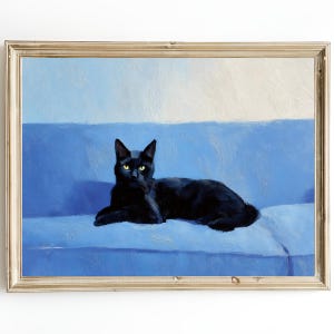 May include: A framed painting of a black cat with yellow eyes resting on a blue sofa. The artwork has a textured, painterly style, with a gold-colored frame. The background is a gradient of blue and white.