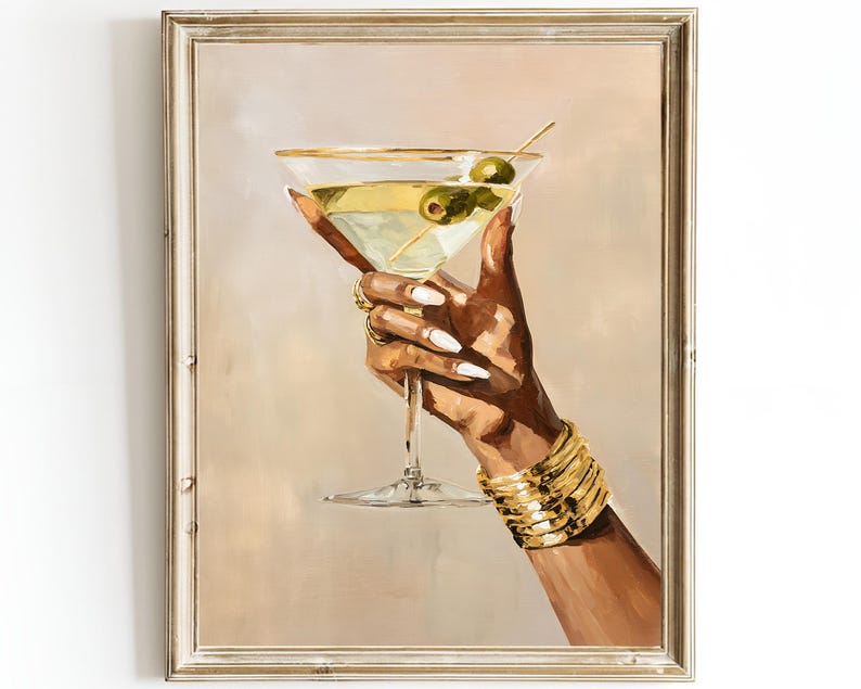 May include: A framed painting depicts a hand holding a martini glass with olives. The glass has a gold rim and is filled with a light green liquid. The hand is adorned with gold jewelry and a gold bracelet. The background is a soft beige.