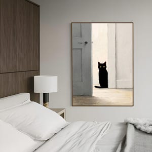 Peut inclure: Une impression d'art encadr&eacute;e repr&eacute;sentant un chat noir aux yeux jaunes dans une embrasure de porte. Le chat est au centre, devant une porte gris clair et des murs blancs. L'&oelig;uvre a un style minimaliste.