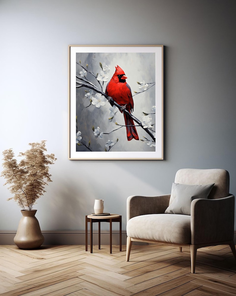 May include: A framed art print featuring a vibrant red cardinal perched on a branch with white blossoms. The artwork is set against a soft, gray background, creating a serene and natural scene. The print is displayed in a living room setting.