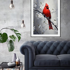 May include: A framed art print featuring a vibrant red cardinal perched on a branch with white blossoms. The artwork is set against a soft gray background, creating a striking contrast. The print is displayed in a living room setting with a blue sofa and decorative elements.