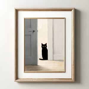 Peut inclure: Impression d'art encadr&eacute;e repr&eacute;sentant un chat noir aux yeux jaunes, assis dans une embrasure de porte. La sc&egrave;ne se d&eacute;roule dans une pi&egrave;ce aux murs blancs et au sol en bois clair. Le cadre est de couleur or clair.