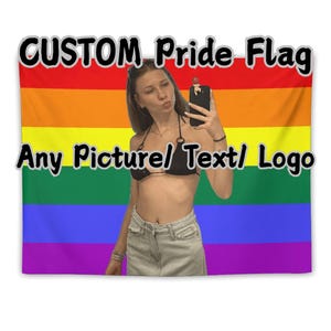 May include: A rainbow Pride flag with the text "CUSTOM Pride Flag" and "Any Picture/ Text/ Logo" in black. The flag has horizontal stripes in red, orange, yellow, green, blue, and purple. A person is in front of the flag.