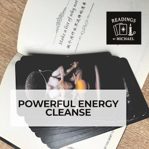 Può includere: Un mazzo di carte dei tarocchi nere con uno striscione bianco con la scritta "POWERFUL ENERGY CLEANSE". Le carte sono sopra un libro aperto con testo in inglese e cinese. Un logo per "READINGS BY MICHAEL" è in alto a destra.