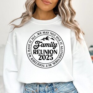 Pu&ograve; includere: Felpa bianca con grafica circolare nera con la scritta "Family Reunion 2025". La grafica include sagome di montagne e il testo "We may not have it all, but together we have it all together."