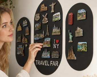 May include: Three oval black magnetic boards for displaying travel souvenirs. The central board features the text TRAVEL FAR and various landmark magnets, including the Eiffel Tower, Route 66, and I heart NY. Additional magnets are on the side boards.