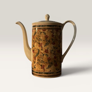 Op de afbeelding: Een hoge, crèmekleurige keramische theepot met een bloemenpatroon in rood, groen en goud. De theepot heeft een lange, gebogen tuit, een afgeronde handgreep en een deksel met een kleine knop. Het bloemendesign bedekt de body van de theepot.