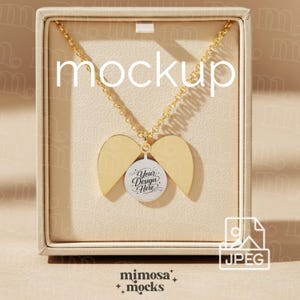 May include: A gold-colored necklace with a pendant in a jewelry box. The pendant has a circular design with the text "Your Design Here" and two wing-shaped elements. The word "mockup" is displayed on the top of the image.