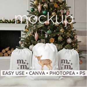 Può includere: Sacchetti bianchi con coulisse con un'illustrazione di cervo e la scritta "m.m." sono esposti davanti a un albero di Natale decorato. Le borse hanno anche la scritta "EASY USE • CANVA • PHOTOPEA • PS".